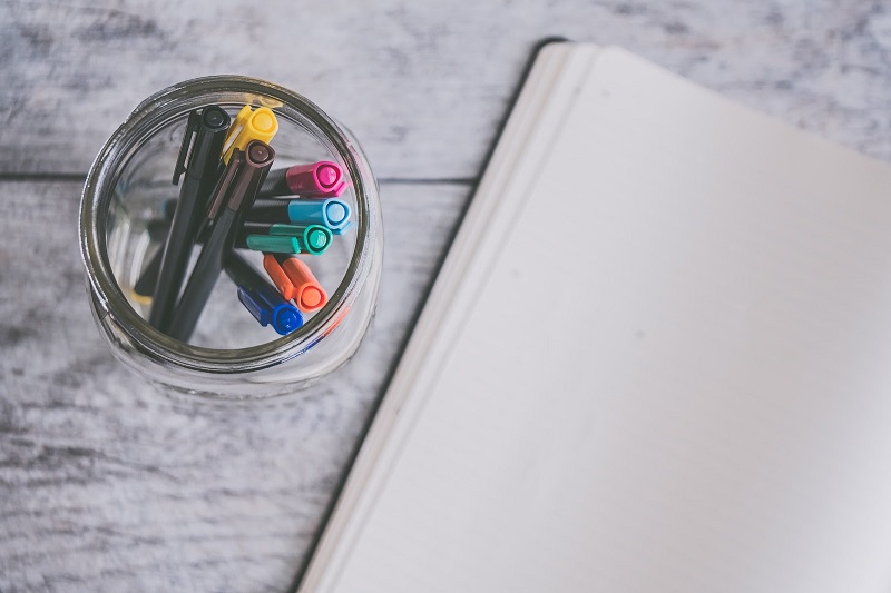 Blank notebook page and markers in a pencil holder