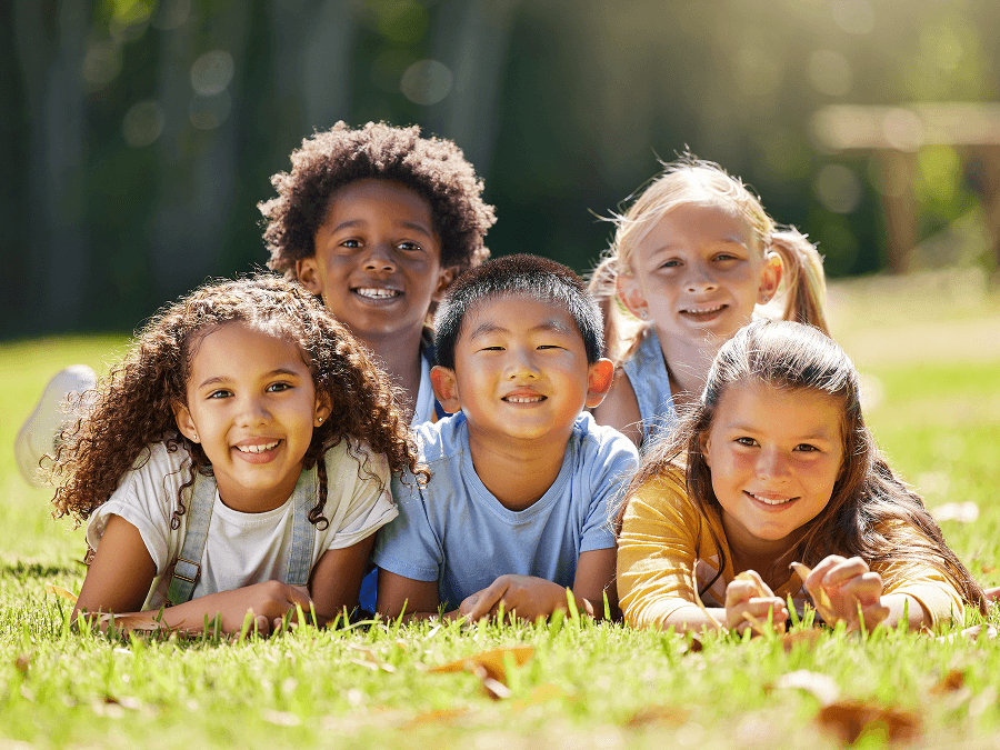 Diverse group of kids laying in the grass smiling