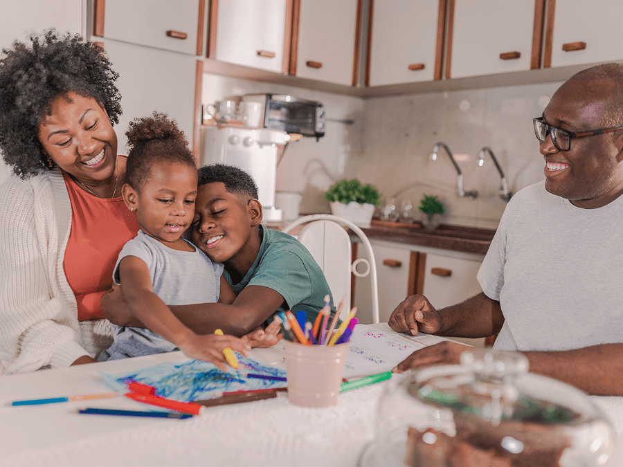 Two adults and two young children coloring at the kitchen table