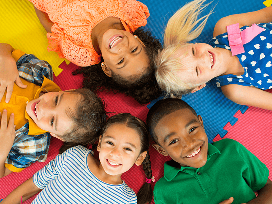 Diverse group of kids laying on a colorful mat in a circle