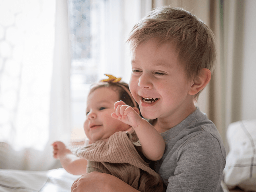 A young boy hugging baby sister