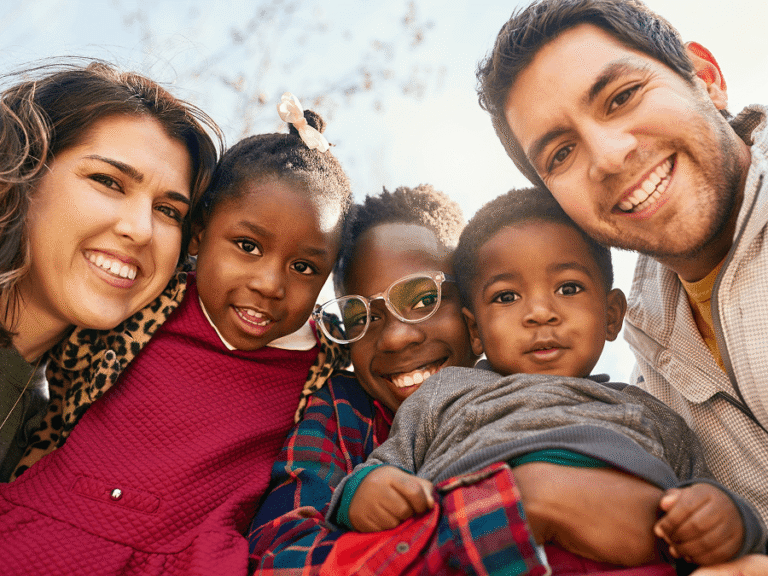 Family with three kids hugging and smiling at camera